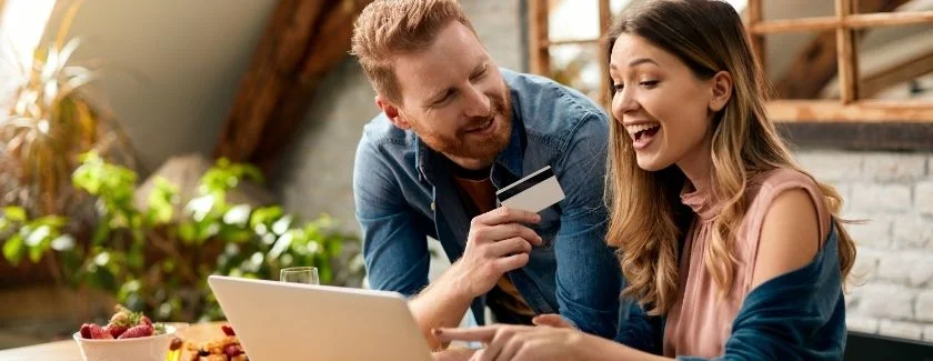 couple talking at computer holding credit card