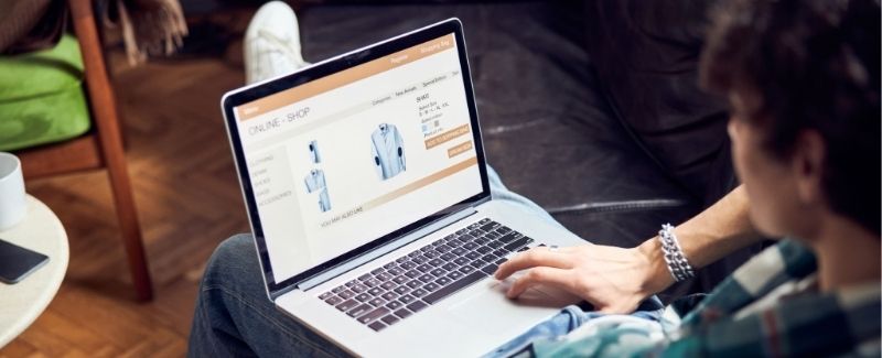man shopping on a laptop sitting on a couch